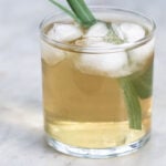 Iced lemongrass tea in a cup with two stalks of lemongrass.