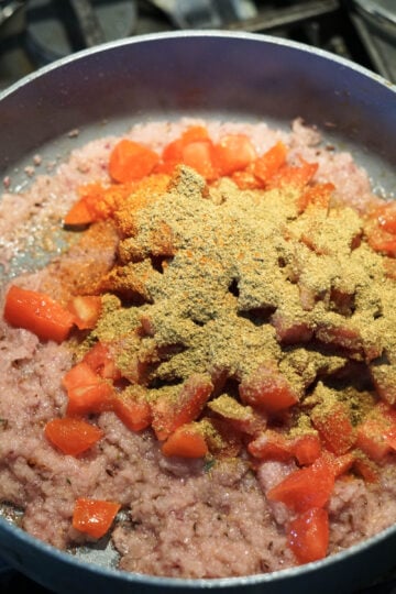 Tomatoes, cumin coriander powder, and salt added to pan.