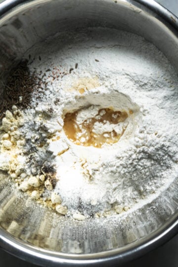 Besan flour, rice flour, spices and oil in a pot.