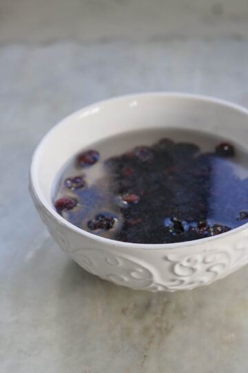Dried cranberries soaking in a bowl of water.