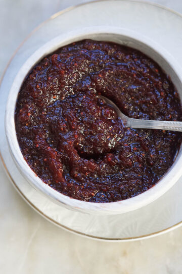 Dried cranberry chutney in a bowl with a steel spoon.