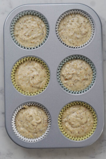 Cupcake batter in cupcake tin for eggless pistachio cupcakes.