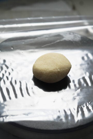 Almond flour roti dough ball on a plastic lined torilla press.