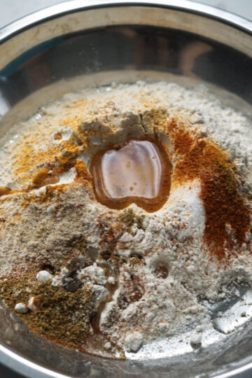 Whole wheat flour, spices, and oil in a pan.