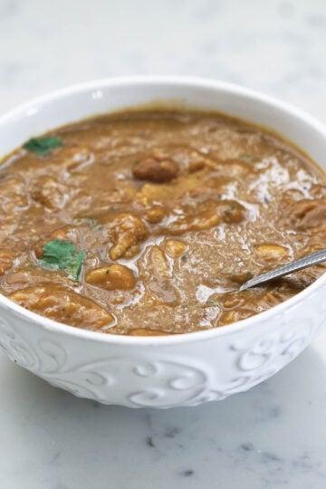 White bowl of dal dhokli with a spoon.