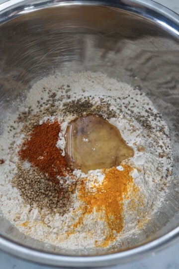 Whole wheat flour, spices, and oil in a well in the center of the flour mixture in a pot.