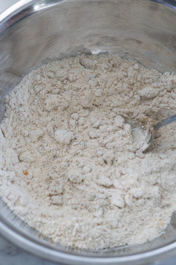 Whole wheat flour, spices, and oil mixed together in a steel bowl.