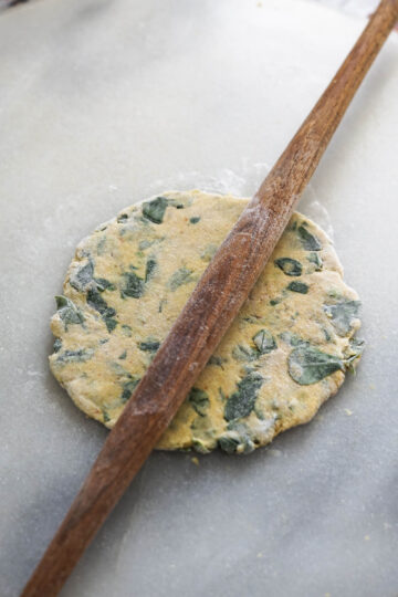 Wooden rolling pin rolling out a methi thepla.