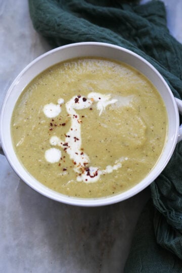 Bowl of curried Indian cauliflower soup with a sprinkle of heavy cream and red chili flakes as a garnish.