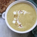 Indian spiced cauliflower soup in a bowl with a piece of toast to the side.