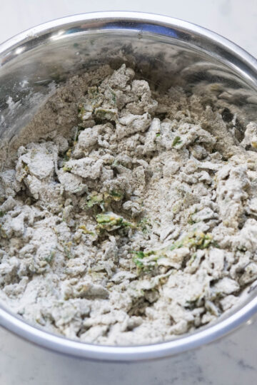 Methi na dhebra dry flour and fenugreek leaves mixture in a steel bowl.