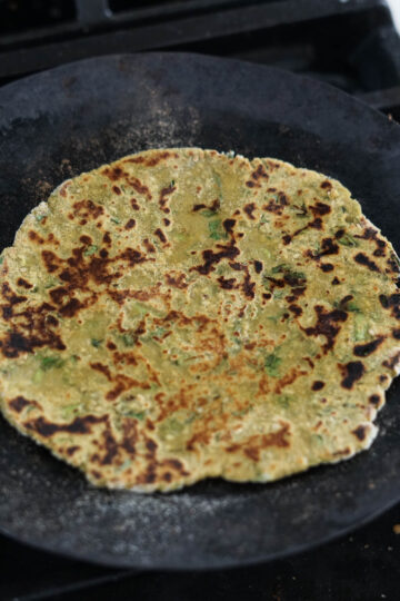 Cooked dhebra with brown spots on a skillet.