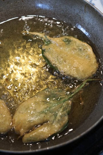 Spinach fritters frying in hot oil.