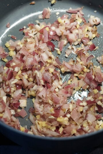 Garlic cloves and ginger added to pan.