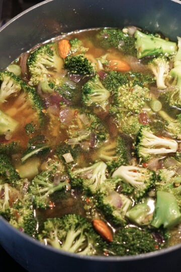 Vegetable stock and spices added to pot.