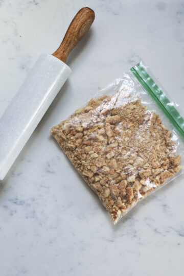 Crushed biscuits in a ziploc bag and a rolling pin to the side.